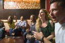 Men and women socializing in a bar in the city. Group of festive, smiling people celebrating with drinks. California USA
